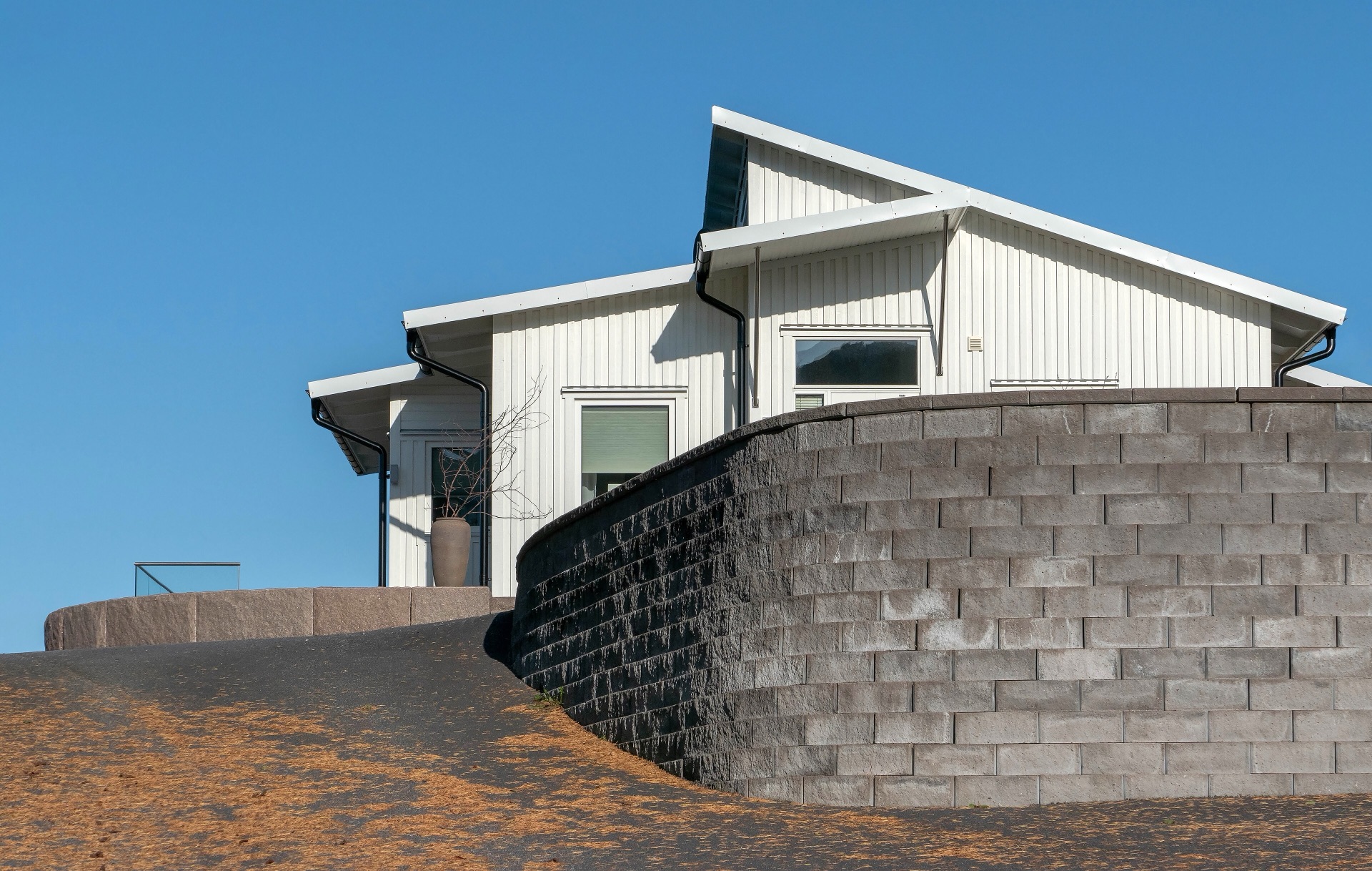 Modernt vitt trähus med pulpettak på en klippa — referensbild, inte ett Kult-bygge.